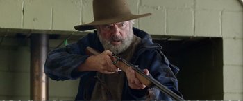 Movie still from “Hunt for the Wilderpeople” (2016), directed by Taika Waititi – An older man holding a rifle in his hands; Close Up shot, Low angle