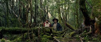 Movie still from “Hunt for the Wilderpeople” (2016), directed by Taika Waititi – A man and a woman standing next to each other in the woods; Wide shot, Low angle