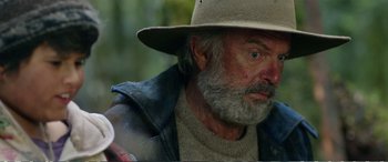 Movie still from “Hunt for the Wilderpeople” (2016), directed by Taika Waititi – An older man wearing a hat and a jacket; Close Up shot, Over the shoulder angle