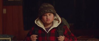 Movie still from “Hunt for the Wilderpeople” (2016), directed by Taika Waititi – A young boy wearing a plaid jacket and a hat; Close Up shot, Low angle