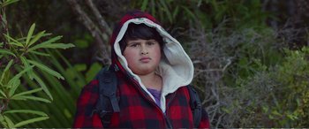 Movie still from “Hunt for the Wilderpeople” (2016), directed by Taika Waititi – A young boy wearing a red and black jacket; Close Up shot, Low angle