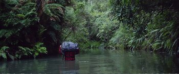 Movie still from “Hunt for the Wilderpeople” (2016), directed by Taika Waititi – A person in the water with a backpack and umbrella; Wide shot, High angle