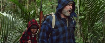 Movie still from “Hunt for the Wilderpeople” (2016), directed by Taika Waititi – A man and a child are walking through the woods; Medium shot, Low angle