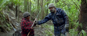 Movie still from “Hunt for the Wilderpeople” (2016), directed by Taika Waititi – A man and a boy holding guns in the woods; Medium shot, Over the shoulder angle