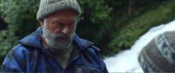 Movie still from “Hunt for the Wilderpeople” (2016), directed by Taika Waititi – An old man with a beard wearing a sweater and a hat; Close Up shot, Over the shoulder angle