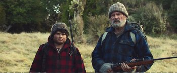 Movie still from “Hunt for the Wilderpeople” (2016), directed by Taika Waititi – A man and a boy with a gun in a field; Medium shot, Over the shoulder angle