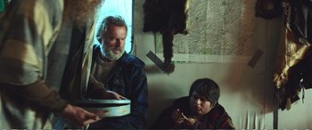 Movie still from “Hunt for the Wilderpeople” (2016), directed by Taika Waititi – A man sitting next to a boy eating food; Medium shot, Over the shoulder angle