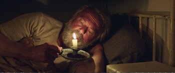 Movie still from “Hunt for the Wilderpeople” (2016), directed by Taika Waititi – An old man laying down with a lit candle in his hand; Close Up shot, High angle
