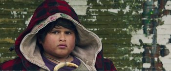 Movie still from “Hunt for the Wilderpeople” (2016), directed by Taika Waititi – A young boy wearing a hooded jacket with a red and black plaid hood; Close Up shot, Low angle