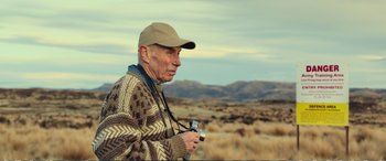 Movie still from “Hunt for the Wilderpeople” (2016), directed by Taika Waititi – An older man holding a camera while standing in a field; Medium shot, Low angle