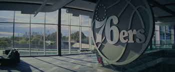 Movie still from “Hustle” (2022), directed by Jeremiah Zagar – A large sign in a room with a large window in the background; Extreme Wide shot, Low angle