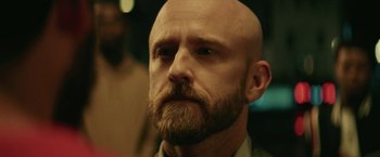 Movie still from “Hustle” (2022), directed by Jeremiah Zagar – A man with a bald head is looking at the camera; Close Up shot, Over the shoulder angle