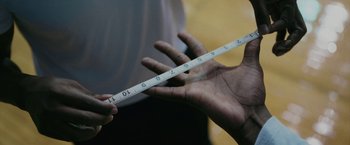 Movie still from “Hustle” (2022), directed by Jeremiah Zagar – A person holding a measuring tape in their hand; Extreme Close Up shot, Overhead angle