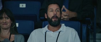 Movie still from “Hustle” (2022), directed by Jeremiah Zagar – A man with a beard is sitting in a stadium; Close Up shot, Over the shoulder angle