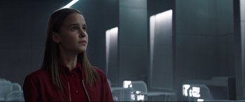 A girl in a red shirt is looking up