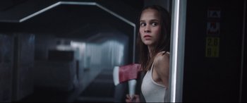 A woman holding a red axe in a dark room