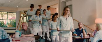 Movie still from “I Care a Lot” (2020), directed by J Blakeson – A group of nurses are holding trays in a room; Medium shot, Over the shoulder angle