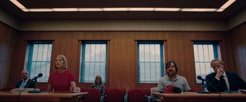Movie still from “I Care a Lot” (2020), directed by J Blakeson – A group of people sitting in a room with red chairs; Wide shot, Low angle
