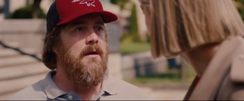 Movie still from “I Care a Lot” (2020), directed by J Blakeson – A man with a beard wearing a red hat; Close Up shot, Over the shoulder angle