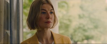 Movie still from “I Care a Lot” (2020), directed by J Blakeson – A person with short hair wearing a yellow jacket; Close Up shot, Over the shoulder angle