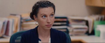 Movie still from “I Care a Lot” (2020), directed by J Blakeson – A woman sitting in front of a stack of books; Close Up shot, Over the shoulder angle
