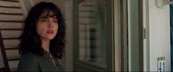 Movie still from “I Care a Lot” (2020), directed by J Blakeson – A young woman with long dark hair standing in front of a mirror; Close Up shot, Over the shoulder angle