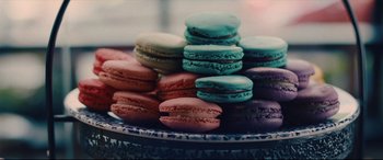 Movie still from “I Care a Lot” (2020), directed by J Blakeson – A plate full of colorful macaroons on the table; Extreme Close Up shot, Overhead angle