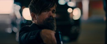 Movie still from “I Care a Lot” (2020), directed by J Blakeson – A man with long hair and a goatee is holding something in his hand; Close Up shot, Over the shoulder angle