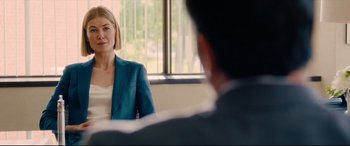 Movie still from “I Care a Lot” (2020), directed by J Blakeson – A woman wearing a blue jacket is sitting in front of a man; Medium shot, Over the shoulder angle