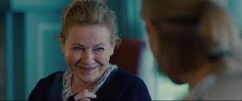 Movie still from “I Care a Lot” (2020), directed by J Blakeson – An older woman smiling at the camera with her hand on her chin; Close Up shot, Over the shoulder angle