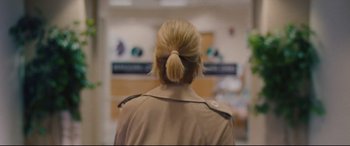 Movie still from “I Care a Lot” (2020), directed by J Blakeson – A woman in a tan jacket is looking into a room; Close Up shot, Over the shoulder angle