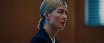 Movie still from “I Care a Lot” (2020), directed by J Blakeson – A person wearing a suit and a ponytail; Close Up shot, Low angle