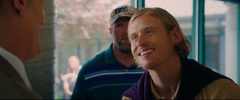 Movie still from “I Care a Lot” (2020), directed by J Blakeson – A man standing next to another man in a purple shirt; Close Up shot, Over the shoulder angle