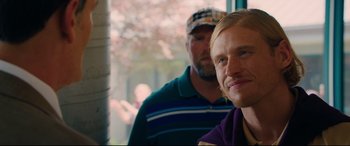 Movie still from “I Care a Lot” (2020), directed by J Blakeson – A man with blonde hair and blue eyes standing next to another man; Close Up shot, Over the shoulder angle