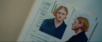 Movie still from “I Care a Lot” (2020), directed by J Blakeson – A man with long blonde hair and a black shirt; Close Up shot, Overhead angle