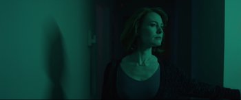 Movie still from “I Care a Lot” (2020), directed by J Blakeson – A woman standing in a dark room with green lighting; Medium shot, Low angle