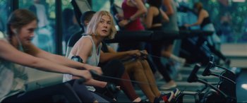 Movie still from “I Care a Lot” (2020), directed by J Blakeson – A group of people in a gym using rowing machines; Medium shot, Over the shoulder angle