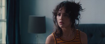 Movie still from “I Care a Lot” (2020), directed by J Blakeson – A woman with curly black hair wearing a yellow and purple striped shirt; Close Up shot, Over the shoulder angle