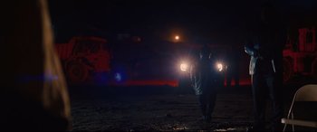 Movie still from “I Care a Lot” (2020), directed by J Blakeson – A man is walking in the dark with headlights on; Wide shot, Low angle
