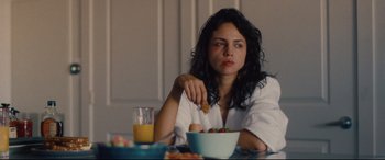 Movie still from “I Care a Lot” (2020), directed by J Blakeson – A woman sitting at a table with a bowl of fruit; Close Up shot, Over the shoulder angle