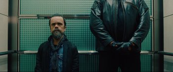 Movie still from “I Care a Lot” (2020), directed by J Blakeson – A man standing next to another man on a train platform; Medium shot, Low angle