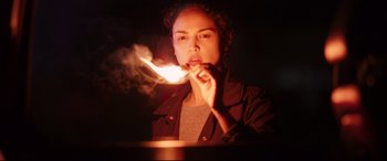 Movie still from “I Care a Lot” (2020), directed by J Blakeson – A woman is lighting a candle in the dark; Close Up shot, Low angle
