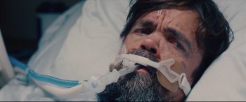 Movie still from “I Care a Lot” (2020), directed by J Blakeson – A man with a beard is holding an oxygen mask in his mouth; Close Up shot, Overhead angle