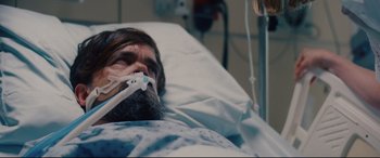 Movie still from “I Care a Lot” (2020), directed by J Blakeson – A bearded man laying in a hospital bed; Close Up shot, Overhead angle