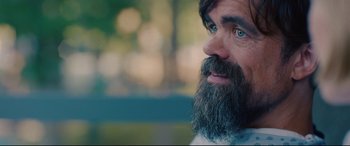 Movie still from “I Care a Lot” (2020), directed by J Blakeson – A man with a long beard and blue eyes looking to his left; Close Up shot, Over the shoulder angle