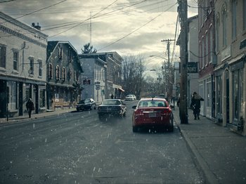 Movie still from “I'm Thinking of Ending Things” (2020), directed by Charlie Kaufman – Cars are driving down the street on a snowy day; Extreme Wide shot, High angle