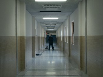Movie still from “I'm Thinking of Ending Things” (2020), directed by Charlie Kaufman – A man standing in a hallway of an office building; Wide shot, High angle