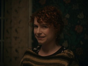 Movie still from “I'm Thinking of Ending Things” (2020), directed by Charlie Kaufman – A woman with red hair is smiling for the camera; Close Up shot, Over the shoulder angle