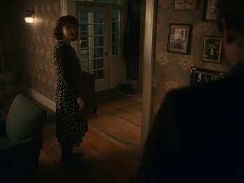 Movie still from “I'm Thinking of Ending Things” (2020), directed by Charlie Kaufman – A woman standing in a room in front of a door; Wide shot, Over the shoulder angle