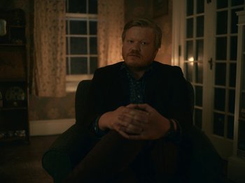Movie still from “I'm Thinking of Ending Things” (2020), directed by Charlie Kaufman – A man sitting in a chair with his hands crossed; Medium shot, Over the shoulder angle